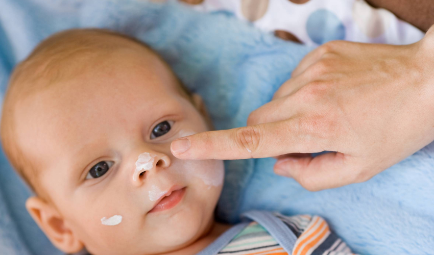 Anne cildi kurumuş bebeğinin tenine losyon sürüyor